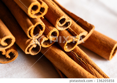 Cinnamon cassia sticks stacked together, showcasing their rich brown color and curled ends. Ideal for culinary and aromatic uses. 136205858