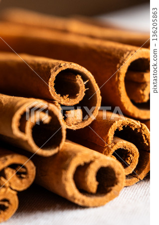Cinnamon cassia sticks stacked together, showcasing their rich brown color and curled ends. Ideal for culinary and aromatic uses. 136205863