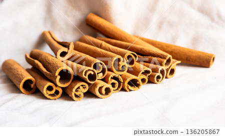 Cinnamon cassia sticks stacked together, showcasing their rich brown color and curled ends. Ideal for culinary and aromatic uses. 136205867