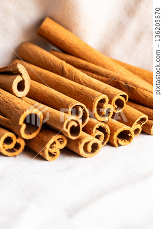 Cinnamon cassia sticks stacked together, showcasing their rich brown color and curled ends. Ideal for culinary and aromatic uses. 136205870