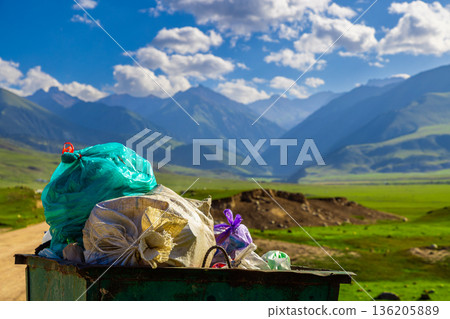 Trash bin filled with garbage bags in serene mountain landscape in Kyrgyzstan Trash bin filled with garbage bags in serene mountain landscape in Kyrgyzstan 136205889
