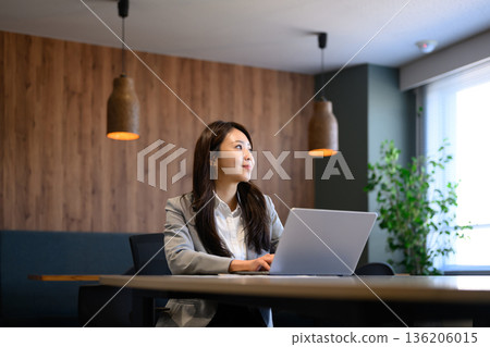 A woman looking into the future with a laptop A woman looking into the future with a laptop 136206015