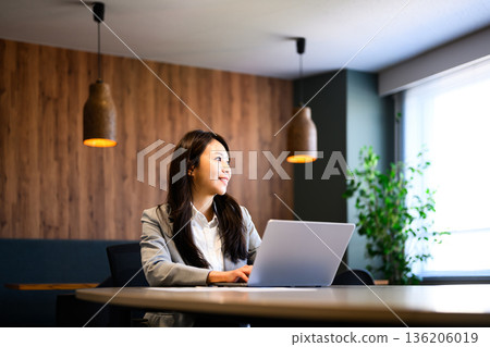 一位女士正在用筆記型電腦休息。 136206019