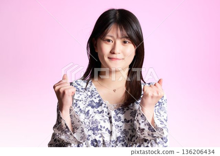 A young woman expressing her motivation by making a fist pump with both hands A young woman expressing her motivation by making a fist pump with both hands 136206434