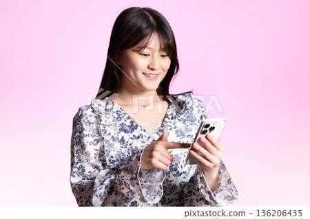 A Japanese woman in her twenties smiling and operating a smartphone A Japanese woman in her twenties smiling and operating a smartphone 136206435