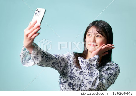 一位面帶微笑的日本女子舉著智慧型手機自拍 一位面帶微笑的日本女子舉著智慧型手機自拍 136206442