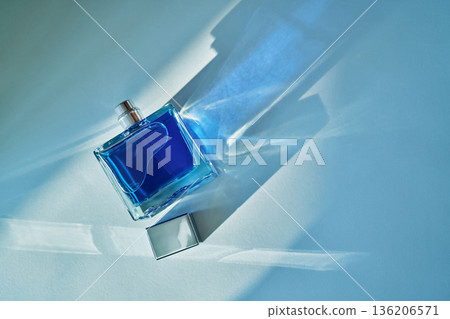 Blue perfume bottle reflecting light creating shadows 136206571