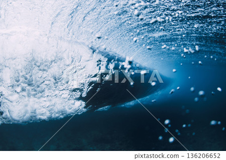 Underwater view inside a breaking ocean wave, blue water with light rays 136206652