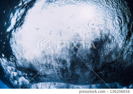 Inside a breaking ocean wave from underwater perspective, dramatic blue tunnel with light, motion and raw power. Inside a breaking ocean wave from underwater perspective, dramatic blue tunnel with light, motion and raw power. 136206656
