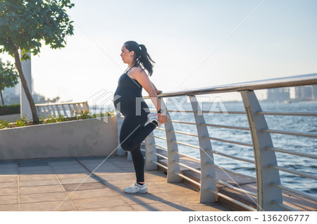 Graceful Prenatal Stretching: Pregnant Woman Balancing By The Water Graceful Prenatal Stretching: Pregnant Woman Balancing By The Water 136206777