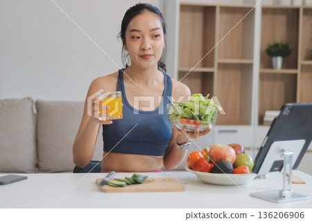 Fit young Asian women in activewear sitting on yoga mat and eating fresh vegetable salad after workout, representing clean eating, fitness lifestyle, wellness routine and health balance. Fit young Asian women in activewear sitting on yoga mat and eating fresh vegetable salad after workout, representing clean eating, fitness lifestyle, wellness routine and health balance. 136206906