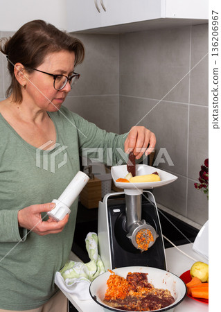 A person prepares liver cutlets on a balcony in autumn. Fresh vegetables and ingredients are being mixed with flour in bowls. Flowers decorate the setting, adding color A person prepares liver cutlets on a balcony in autumn. Fresh vegetables and ingredients are being mixed with flour in bowls. Flowers decorate the setting, adding color 136206967