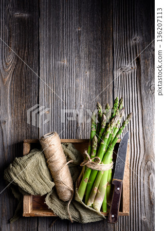 Fresh green asparagus arranged on wooden crate with fabric napkin Fresh green asparagus arranged on wooden crate with fabric napkin 136207113