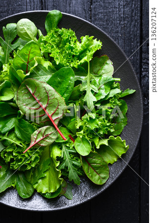 Fresh mix salad leaves arranged on black plate Fresh mix salad leaves arranged on black plate 136207124