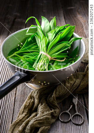 Fresh wild garlic in colander with rustic background Fresh wild garlic in colander with rustic background 136207143