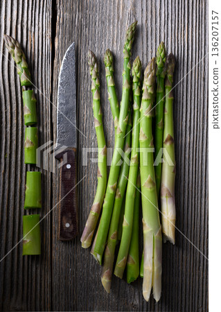 Green asparagus spears arranged on rustic wooden table with knife 136207157