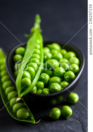 Green peas served in a black ceramic bowl 136207159
