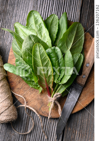 Green sorrel foliage on circular chopping board 136207162