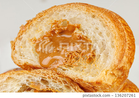 Mouth-watering croissant with boiled condensed milk. Close up of flaky pastry with sweet filling. 136207261