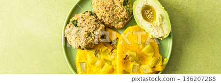 A colorful breakfast spread featuring scrambled eggs mixed with rhubarb, quinoa pancakes, and sliced avocado drizzled with olive oil, all served on a green plate, banner 136207288