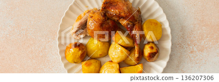 A delicious plate showcases a portion of baked rabbit alongside tender, golden roasted potatoes. The rabbit appears well-seasoned, with a crispy skin, while the potatoes are perfectly cooked, banner 136207306
