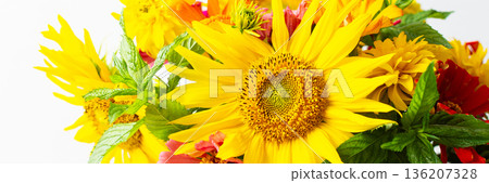 Flowers in a vase fill a space with color and texture. Sunflowers, zinnias, and greenery are mixed together. Light brightens the scene, showcasing their vibrant colors, banner 136207328