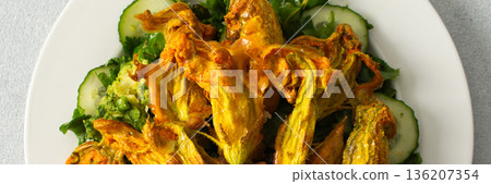 Roasted zucchini flowers sit on a bed of salad made with fresh greens, cucumbers, and broccoli. This dish highlights summer flavors and healthy eating options, banner Roasted zucchini flowers sit on a bed of salad made with fresh greens, cucumbers, and broccoli. This dish highlights summer flavors and healthy eating options, banner 136207354