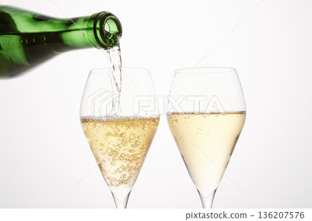 Sparkling wine pours from green bottleneck, creates bubbles. Sparkling wine pours from green bottleneck, creates bubbles. 136207576