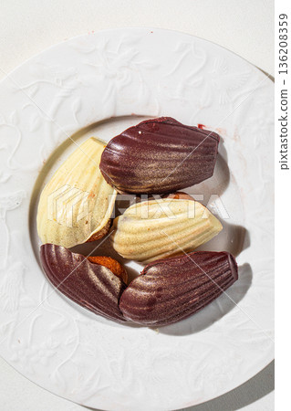 Assorted chocolate madeleine cakes on white plate Assorted chocolate madeleine cakes on white plate 136208359