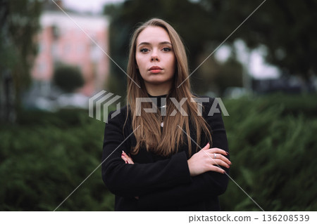 Confident Young Woman Portrait Outdoors Wearing Black Jacket Standing in Urban Park with Soft Green Background and Natural Daylight Confident Young Woman Portrait Outdoors Wearing Black Jacket Standing in Urban Park with Soft Green Background and Natural Daylight 136208539