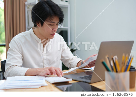 Startup businessman analyzing investment data while studying digital marketing strategy online Startup businessman analyzing investment data while studying digital marketing strategy online 136208576