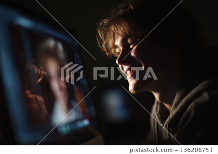 Smiling student engaged in digital creativity reflected in the screen 136208751