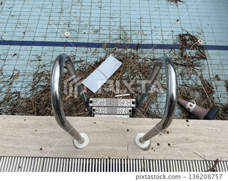 Empty swimming pool with debris and ladder. Concept of maintenance or seasonal pool closure 136208757