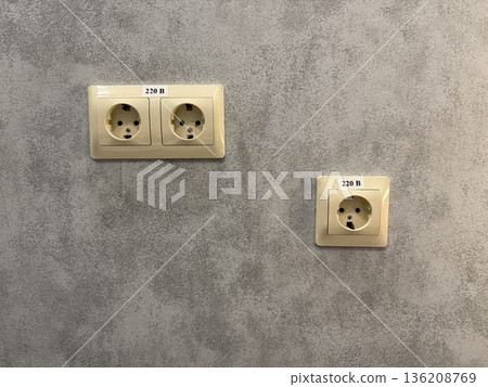 Electrical wall sockets on textured concrete wall background with space for copy or design Electrical wall sockets on textured concrete wall background with space for copy or design 136208769