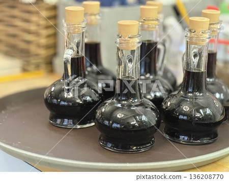 Bottles of balsamic vinegar with wooden caps arranged on tray in kitchen setting Bottles of balsamic vinegar with wooden caps arranged on tray in kitchen setting 136208770