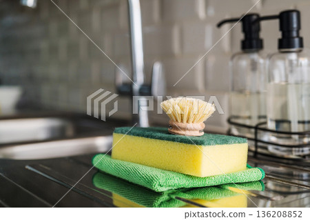Wooden brush for washing dishes in the kitchen next to sink. Eco friendly, zero waste or conscious consumption concept. Copy space Wooden brush for washing dishes in the kitchen next to sink. Eco friendly, zero waste or conscious consumption concept. Copy space 136208852