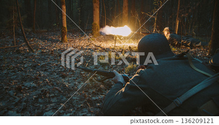 German soldier firing rifle with bright muzzle flash in night forest battle 136209121