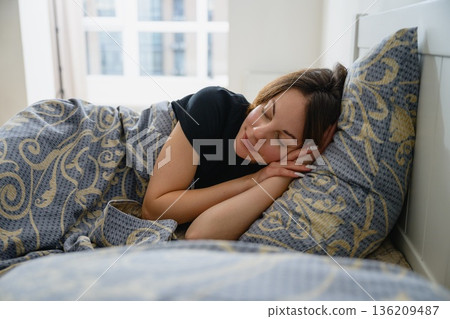 Young woman sleeping on her side in a cozy bedroom 136209487
