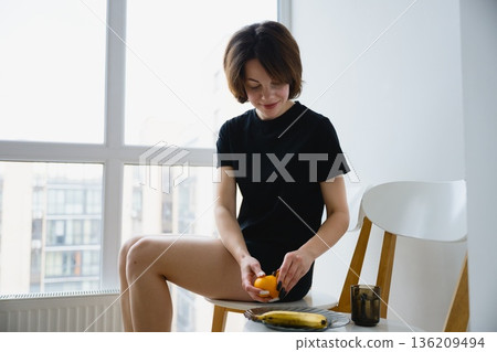 Woman eating fruit and enjoying calm morning at home Woman eating fruit and enjoying calm morning at home 136209494