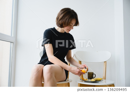 Woman eating fruit and enjoying calm morning at home 136209495