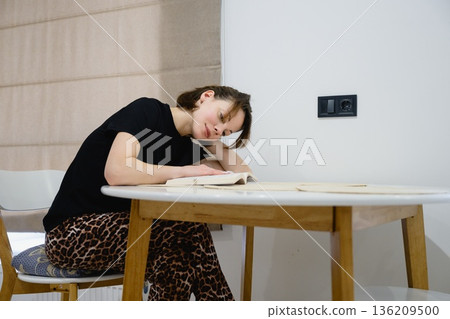 Woman reading book at table in modern kitchen 136209500