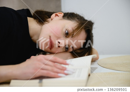 Woman reading book at table in modern kitchen 136209501