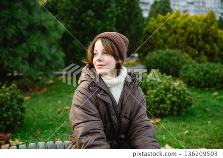 Woman sitting in park during autumn season 136209503