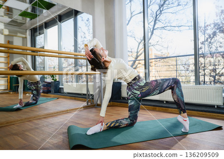 Woman practicing low lunge yoga pose with backbend in studio 136209509