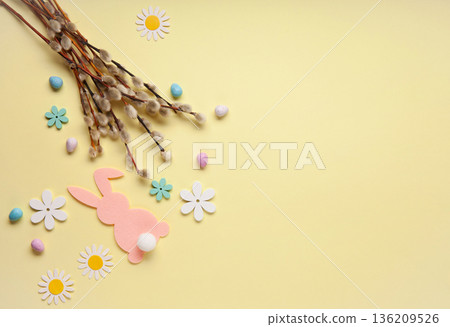 Easter spring holiday card. Playful bunny, painted eggs, willow branches, paper flowers, decorative elements on yellow background Easter spring holiday card. Playful bunny, painted eggs, willow branches, paper flowers, decorative elements on yellow background 136209526