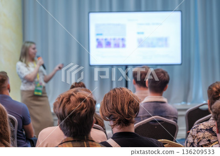 Presenter speaks to engaged audience at conference with screen displaying slides and notes Presenter speaks to engaged audience at conference with screen displaying slides and notes 136209533
