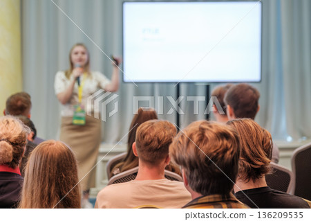 Presenter delivers talk to attentive audience at conference with large screen projection during session Presenter delivers talk to attentive audience at conference with large screen projection during session 136209535