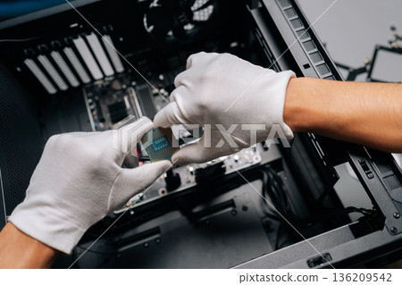 Closeup of computer technician wearing protective gloves positioning microprocessor onto electronic circuit board, demonstrating professional hardware maintenance and intricate technical assembly. 136209542