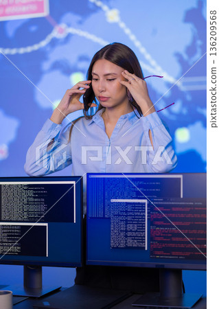 Female analyst monitoring cybersecurity threats in a control room setting Female analyst monitoring cybersecurity threats in a control room setting 136209568