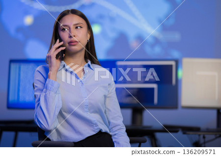 Confident cybersecurity professional analyzing data while communicating in a monitoring environment Confident cybersecurity professional analyzing data while communicating in a monitoring environment 136209571